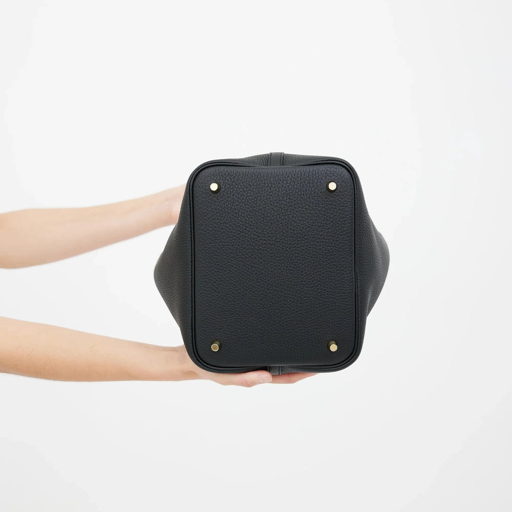 Black leather bag held by a person on a white background