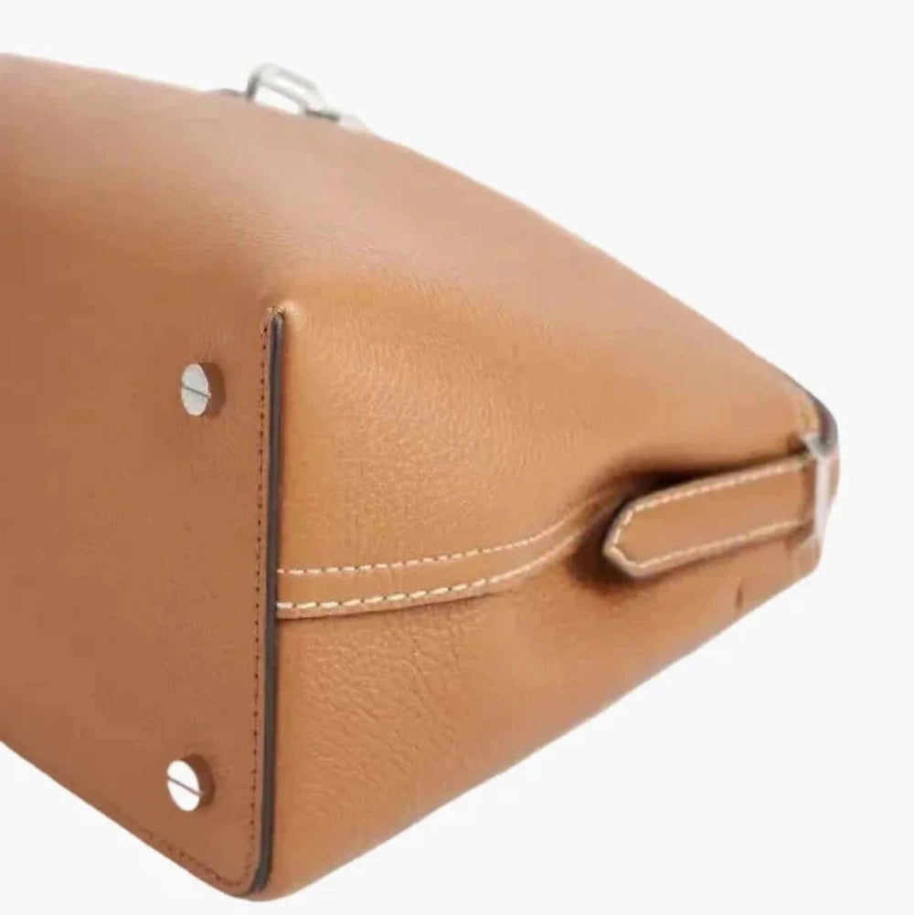 Close-up of a brown leather handbag with visible stitching on a white background